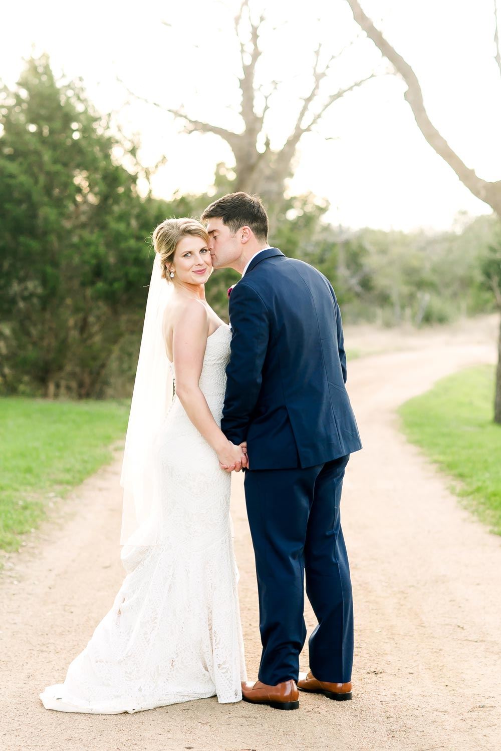 Сouple wearing a white gown and a blue suit on the road
