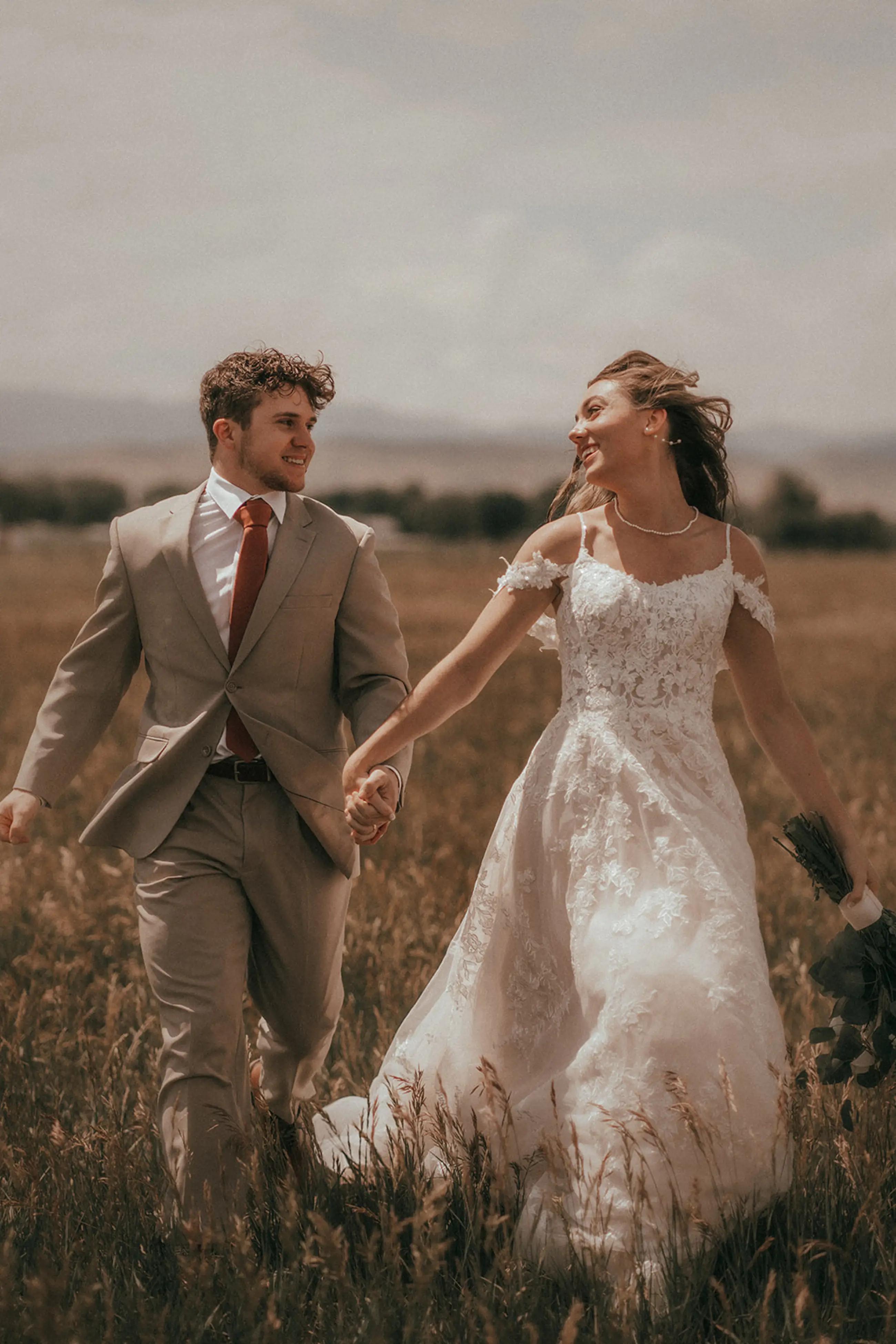 Сouple wearing a white gown and a gray suit on  the field