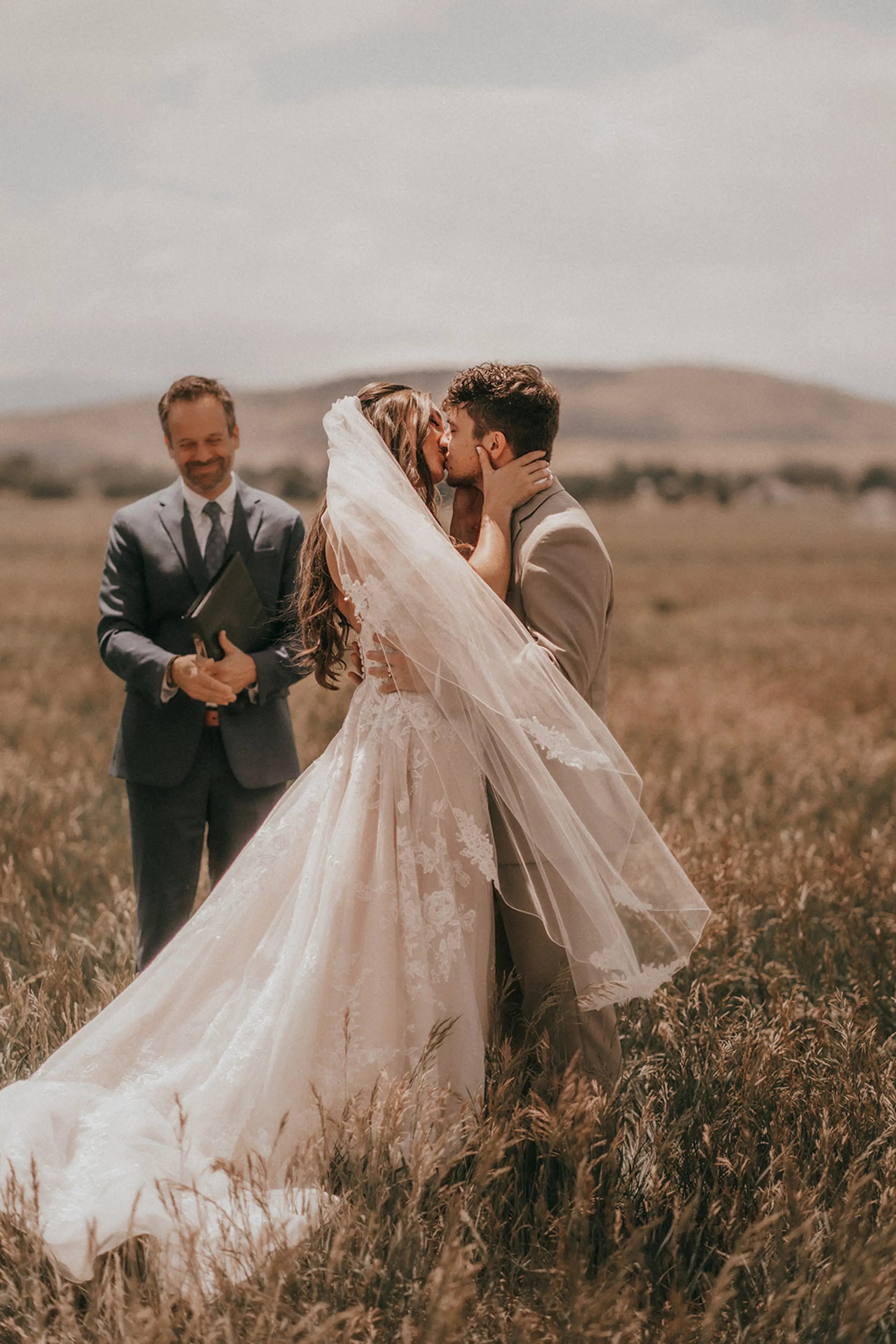 Kissing couple wearing a white gown and a black suit on the field